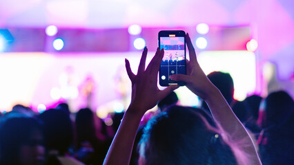 Girl holding smart phone and recording and photographing in music festival concert, event...