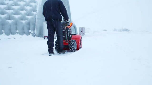 Man working with snowblower near the helicopter hangars 