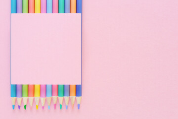 A school background with pastel colored pencils and a pink sticker on a pink background.The concept...