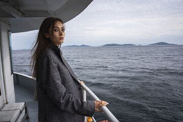 Istanbul. Asian girl in a man's jacket sails on a ferry in Istanbul in cloudy weather