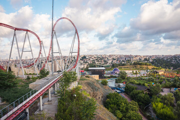 Roller coaster in an amusement park located on a hill on a sunny cloudy day