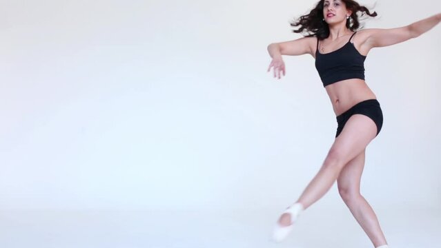 Beautiful young dancer in pointes dancing in light studio