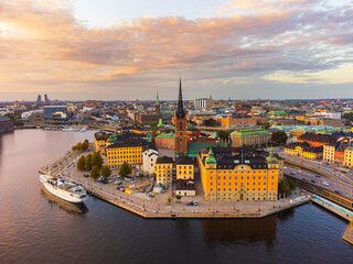 Fototapeta premium Panorama of the old city, downtown Stockholm and of the island of Riddarholmen in late evening sun, aerial view, yellow colors, pink sky