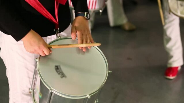 Male hands playing on white drum on stage at concert