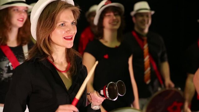 Musical group of eight people play drums and other instruments