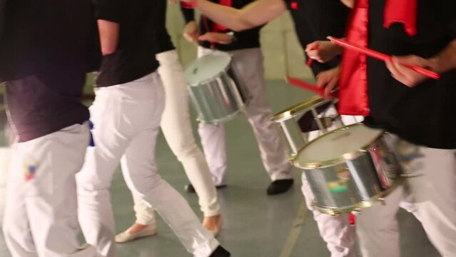 Musical group of thirteen people play drums on stage 