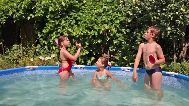 Happy boy and two girls play sticky tennis in swimming pool 
