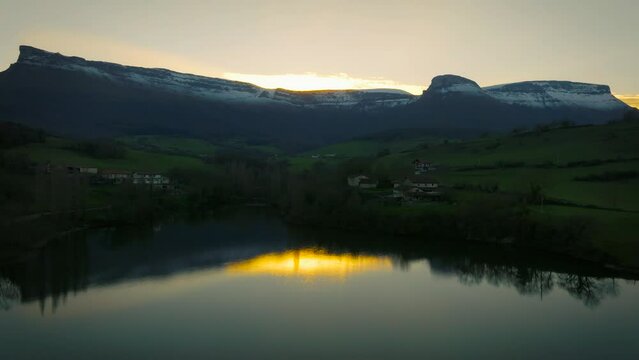 Reflejo de las monta&ntilde;as en el lago con un atardecer dorado.
