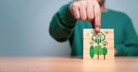 Businessman holding wooden cube CO2 reducing icon and tree for decrease CO2 emission, carbon...