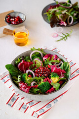 salad in a ceramic plate with green lettuce, pomegranate and red onion, without people, close-up