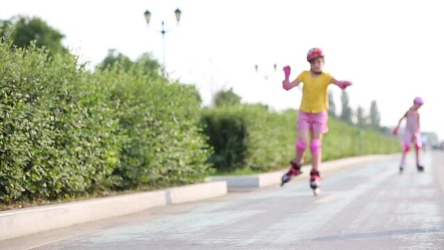 Girl in elbow pads and knee pads roller-skating on one leg