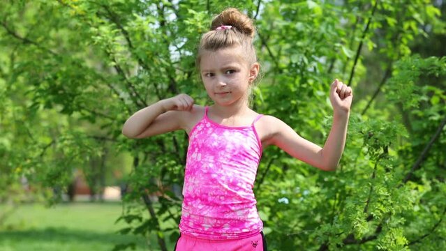 Little girl in pink limbers up among greenery at spring park.