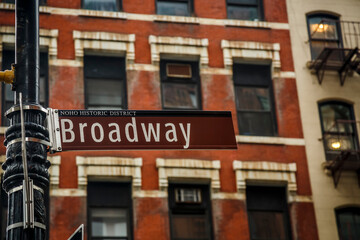 Broadway sign with red brick wall facade background in NYC, USA