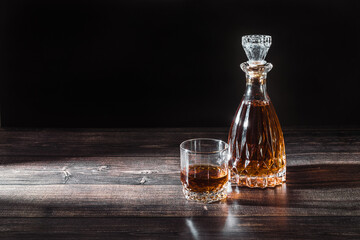 A glass decanter and a glass with a drink in a beam of light