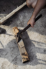 A man chops wood with an ax to light a fire. Backyard work.