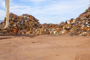 Dump of old rusty scrap metal and crane boom with grabbing steel claws.