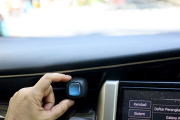 The female driver's hand puts car perfume on the AC grill. perfume packaged in bottles and wooden caps. car air freshener.