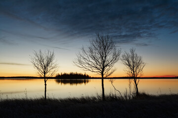 Fototapeta premium Early autumn morning by a lake with vivid colors of the sky reflecting on the surface of the water