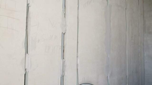 Plastered wall with plurality of wires in room 