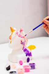 Girl paints a clay figure with paints