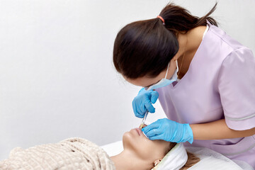 Obraz na płótnie Canvas beautician makes injections to enlarge the lips of beautiful woman. procedure lip augmentation
