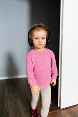 A beautiful little girl is listening music in headphones. Happy smiling child enjoys listens to music