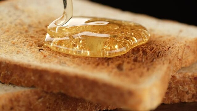 Zoom frame honey pouring on sliced toast bread. Healthy breakfast concept