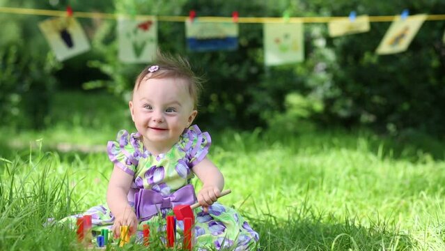 baby plays with wooden metallofon on green grass