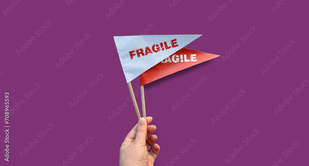 Wall mural small paper flags in hand with the warning 'fragile' as a label. the concept of fragile products. mo