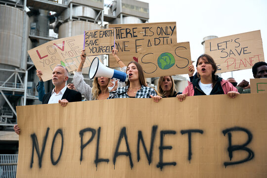 Group diverse people of demonstrators protesting against climate change. Woman shouting with a megaphone banners at a march in favor of the environment. - Powered by Adobe