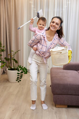 happy mother housewife is holding cute little child girl and basket with laundry and doing housework at home , Happy family