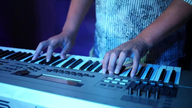 Hands of man playing keyboard in night club at show