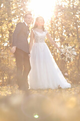 Fototapeta na wymiar beautiful bride in white wedding dress and groom standing outdoor on natural background in sunny day