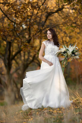 Obraz na płótnie Canvas beautiful happy bride holding wedding autumn bouquet in nature