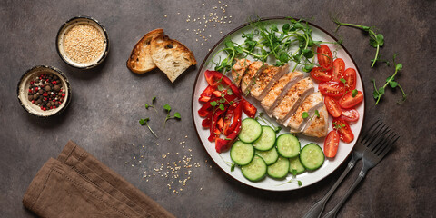 Grilled chicken fillet with fresh vegetables on a dark rustic background. Top view, flat lay. Banner