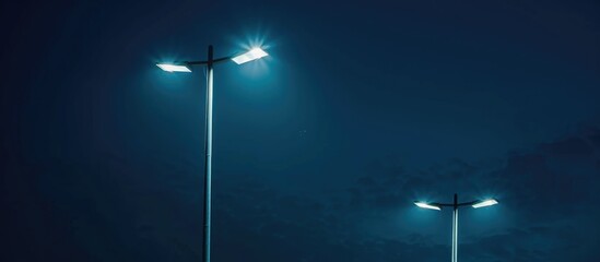 Contemporary urban street lights powered by electricity, shining against the dark night sky.