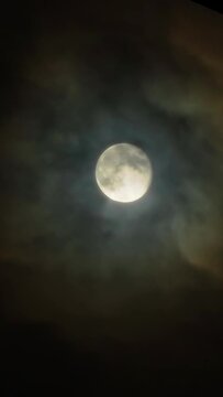 Full moon in the dark night sky. The Moon Corona is a light optical phenomenon in the form of colored clouds around the Moon. Shot through a telephoto lens