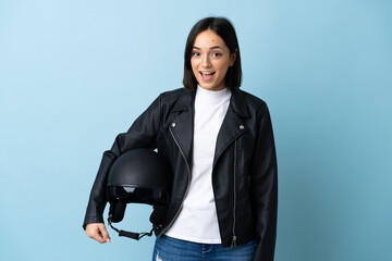 Woman holding a motorcycle helmet isolated on blue background with surprise facial expression