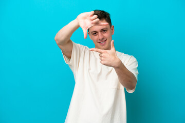 Fototapeta premium Young handsome Brazilian man isolated on blue background focusing face. Framing symbol