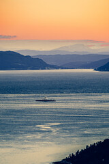 Majestic mountains by the fjord at sunset - orange sky in the mountains.