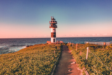 Lonely lighthouse in sunset on the coast of Galicia, Spain. Island of Pancha (Isla Pancha) clote to...