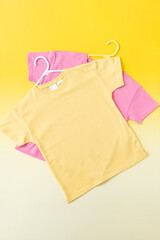 Yellow and pink children's T-shirts on a yellow background. Flat lay. 