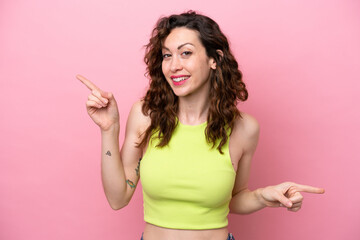 Young caucasian woman isolated on pink background pointing finger to the laterals and happy