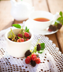 Fresh berries and cup of tea on table