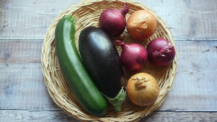 Selection of fresh healthy vegetables in a basket, courgette, aubergine, oniions