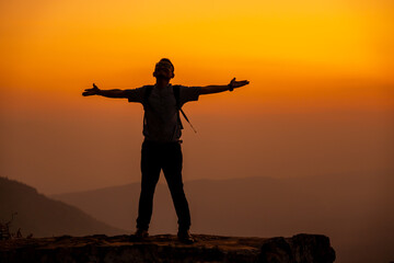 Fototapeta na wymiar Man tourist on the cliff of the mountain on sunset background