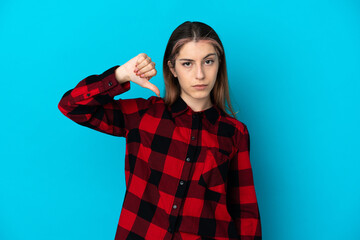Young caucasian woman isolated on blue background showing thumb down with negative expression