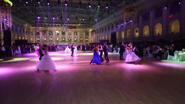 Couples dance under purple lights at 11th Viennese Ball