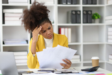 Stress and pressure of overwork. African woman in office stressed with paperwork and worried about not meeting deadlines.