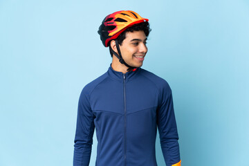 Venezuelan cyclist man isolated on blue background looking side